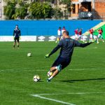 Soccer player in action during practice on a sunny day, kicking the ball on a green field.
